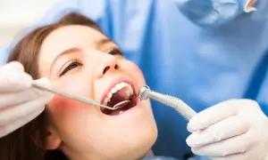 Pacjentka z otwartymi ustami, dentysta bada jej zęby. Widoczna jest przetoka na dziąśle.