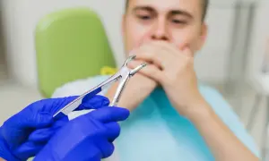 Pacjent zakrywa usta po zabiegu, zastanawiając się, czy po wyrwaniu zęba można wychodzić na dwór.