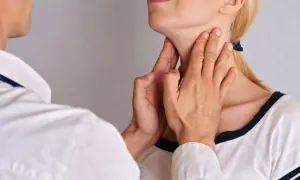 Lekarz bada węzły chłonne głowy pacjentki, delikatnie dotykając jej szyi.