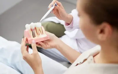 Dentysta wyjaśnia pacjentce budowę implantu zębowego, odpowiadając na pytanie: czy implanty są bezpieczne.