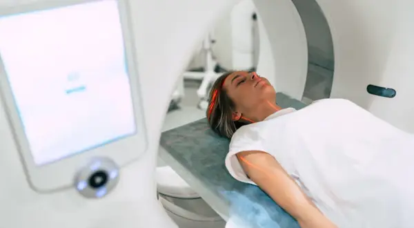 Kobieta leży na stole do rezonansu magnetycznego. Czerwone linie lasera wskazują obszar badania. Ważne są rezonans magnetyczny przeciwwskazania.