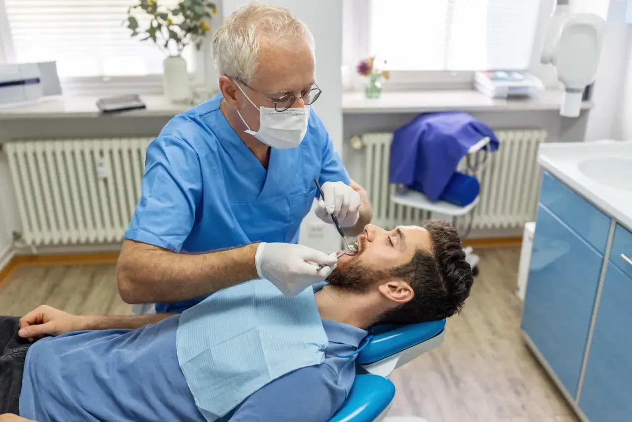 Dentysta bada pacjenta. Zastanawiasz się, ile kosztuje usunięcie ósemki na NFZ? Wizyta u stomatologa to pierwszy krok.