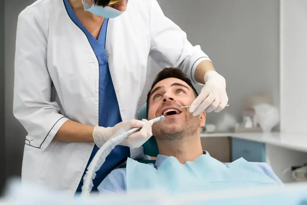 Dentysta wykonuje zabieg w sedacji u pacjenta, który wygląda na zrelaksowanego.